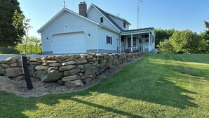 A two-story house with a stone retaining wall, a garage, and a covered porch.
