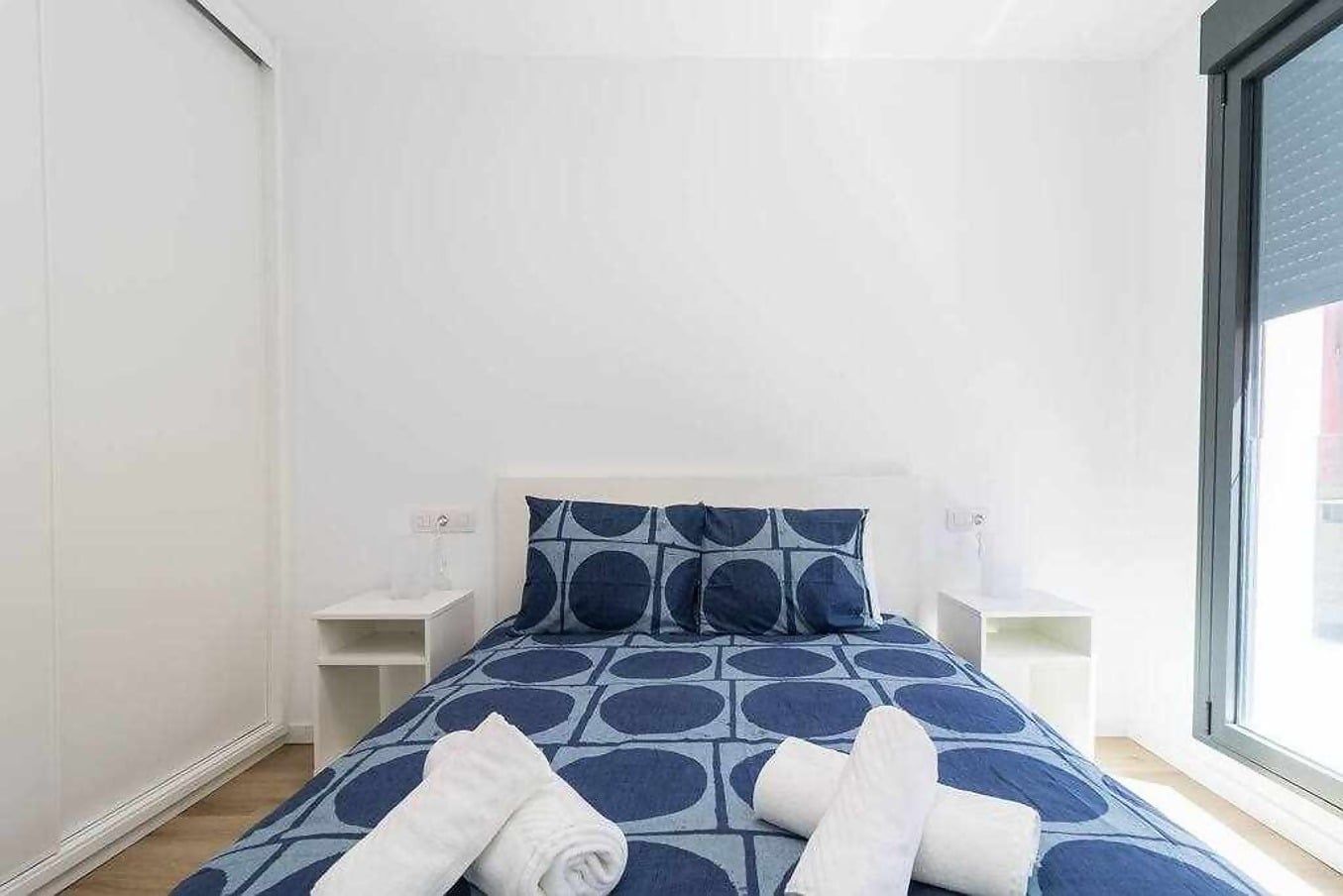 A bedroom with a bed, two bedside tables, and a window.