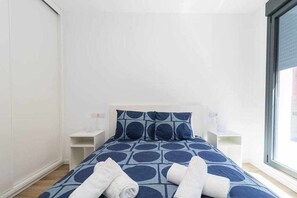 A bedroom with a bed, two bedside tables, and a window.