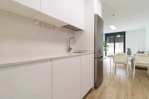Een moderne keuken met witte kasten, een roestvrijstalen koelkast en een spoelbak.
