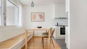A compact kitchen with a dining area, a window, and a framed artwork on the wall. - Superb Gellert 2 Room w/ Storage Room, nr Tram & Market, by Blueground (Basel)