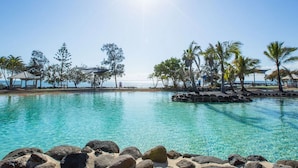 A clear blue pool with rocks in the foreground, surrounded by trees and a gazebo. - "Suttons Beach Breeze" - Margate Q 4109 (Margate)