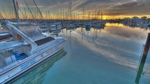A marina with multiple boats docked, calm water, and a sunset in the background. - "Suttons Beach Breeze" - Margate Q 4109 (Margate)