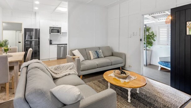 A modern living room with a grey sofa, a wooden coffee table, and a kitchen in the background. - "Suttons Beach Breeze" - Margate Q 4109 (Margate)