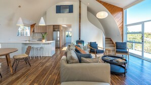 A spacious living area with a large sofa, a dining table, and a kitchen in the background.