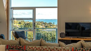 A living room with a large window offering a view of a coastal landscape.