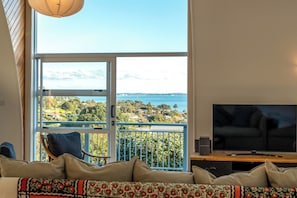 Sala de estar com uma janela ampla que oferece vista para a paisagem costeira.