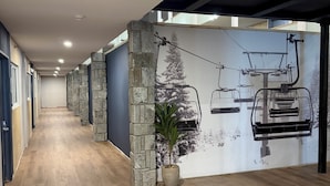 Un pasillo con suelo de madera, paredes de piedra y un mural de un telesilla.