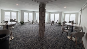Un salón de conferencias con un pilar de piedra, ventanas amplias y mobiliario moderno.