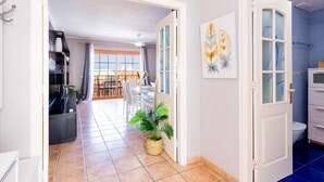 A hallway with a dining area, a potted plant, and a view to the outside. - 21 C Apartamento Las Bouganvillas (Costa Adeje)