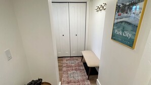 Un pasillo con un banco, un tapete estampado y un cuadro en la pared.