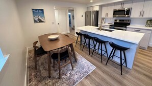 Una cocina moderna con una isla central, taburetes de bar y electrodomésticos de acero inoxidable.
