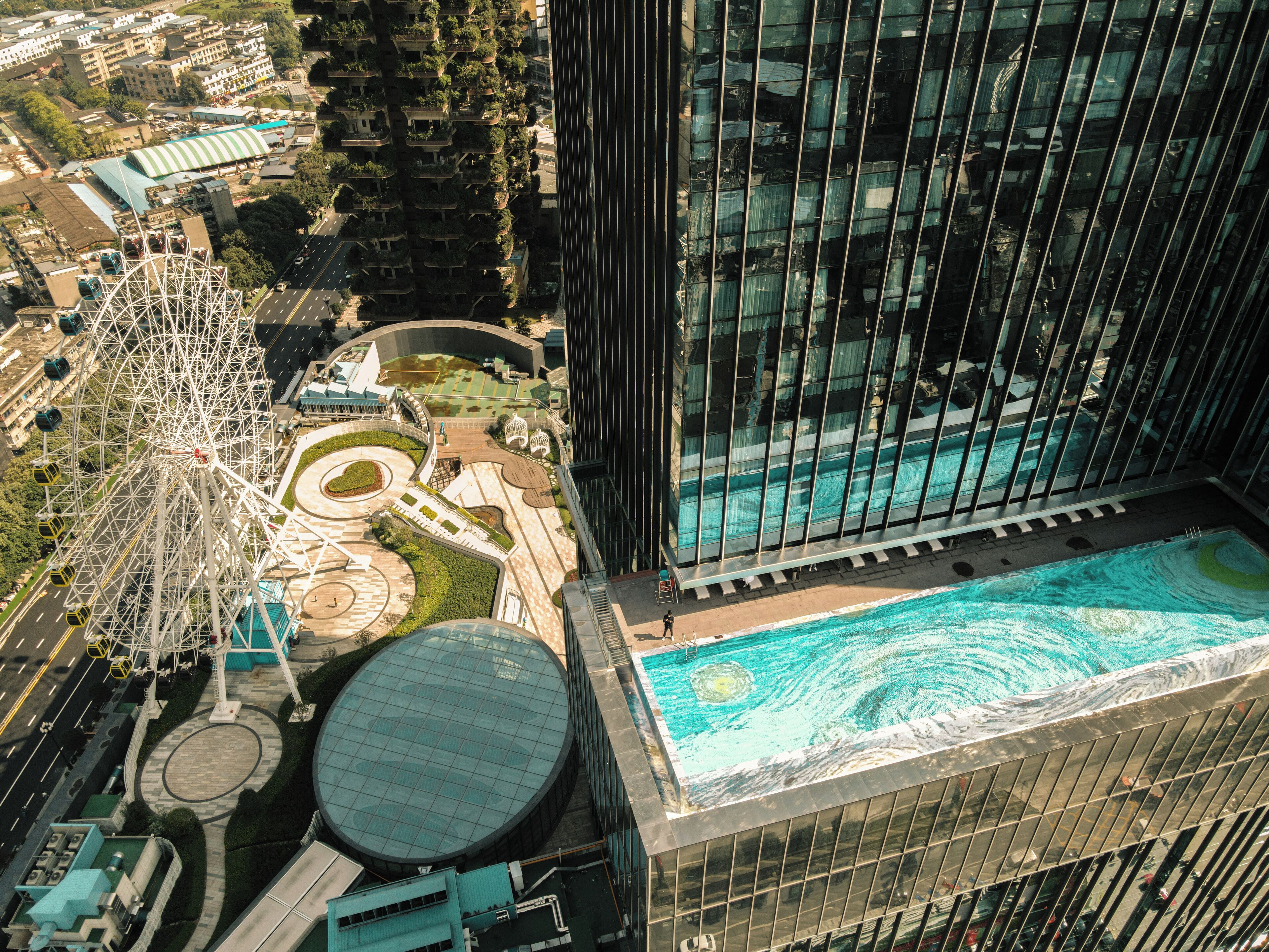 Un edificio alto con piscina en la azotea y una noria.
