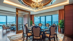 Uma ampla área de jantar com uma mesa redonda, cadeiras elegantes e um candelabro.
