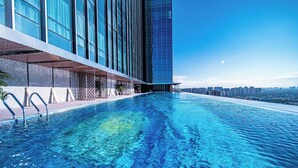 Um hotel moderno com piscina infinita no terraço, vista para o horizonte da cidade e fachada imponente.