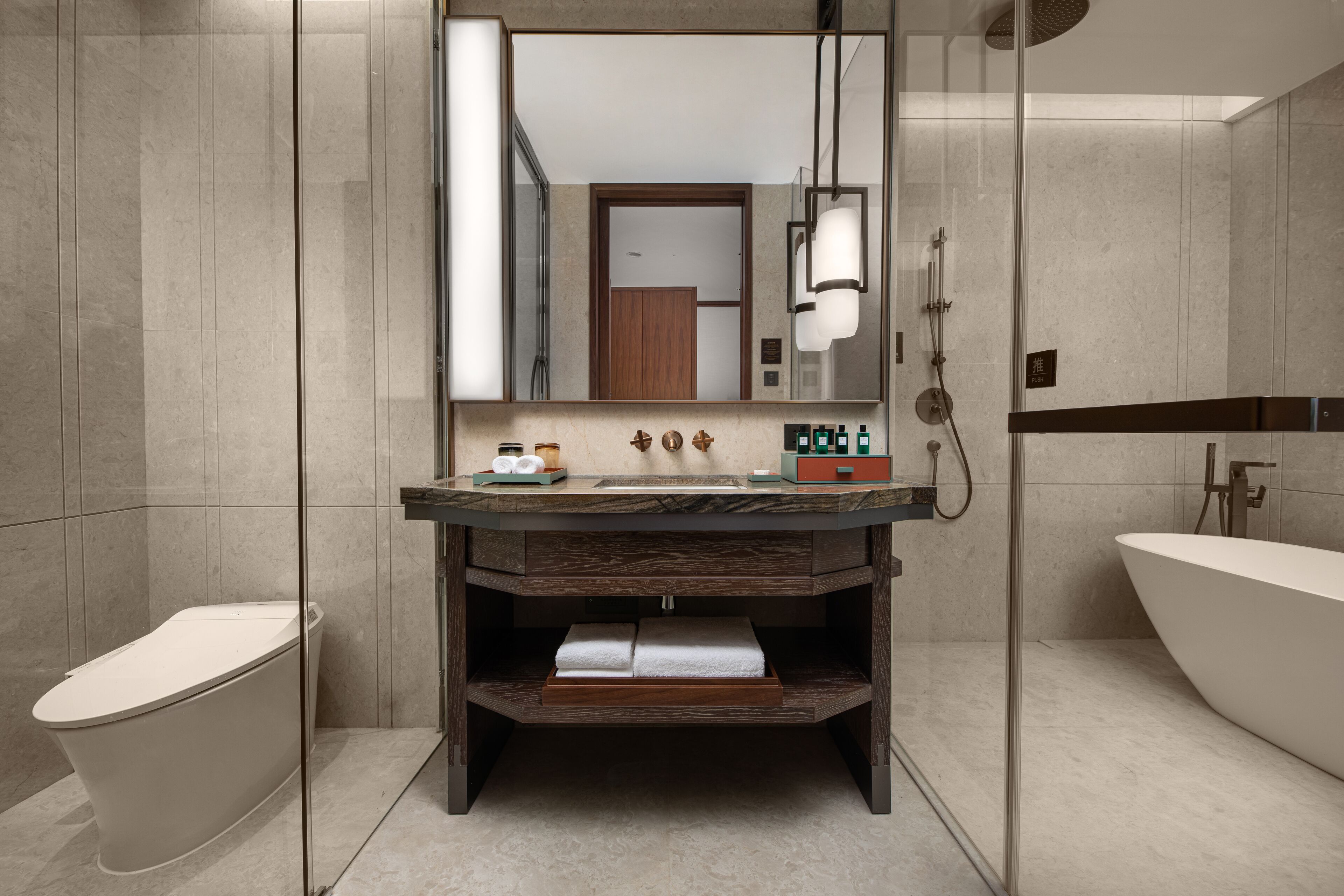 A modern bathroom with a freestanding bathtub, a glass-enclosed shower, and a vanity with a mirror and lighting.