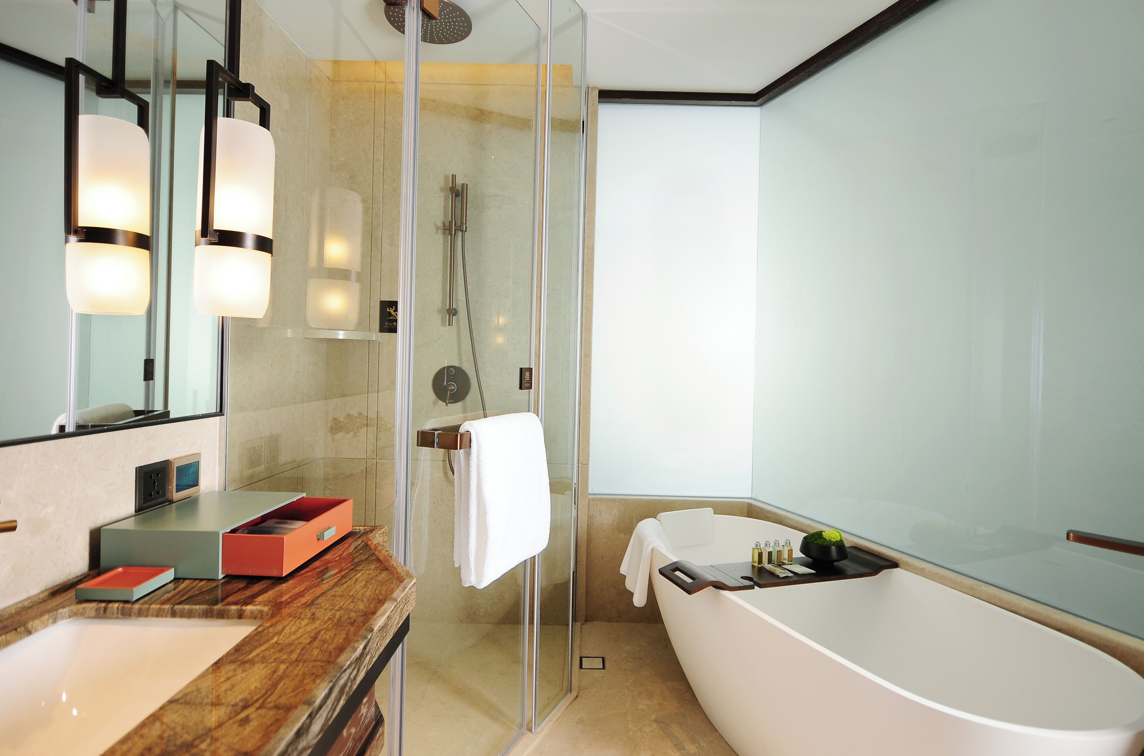 Un baño moderno con ducha de vidrio, una bañera grande y un tocador con espejo y cajones.