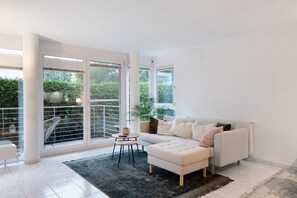 Un salon moderne avec un canapé, un pouf et une petite table.