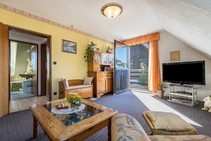 A living room with a glass coffee table, a sofa, a television, and a view of the outside. - Apartment 'Am Ps Speicher' with Balcony and Wi-Fi (Einbeck / Wenzen)