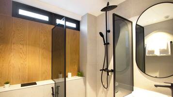 Un baño moderno con tocador de madera, un espejo grande y ducha con cabezal de ducha de mano.