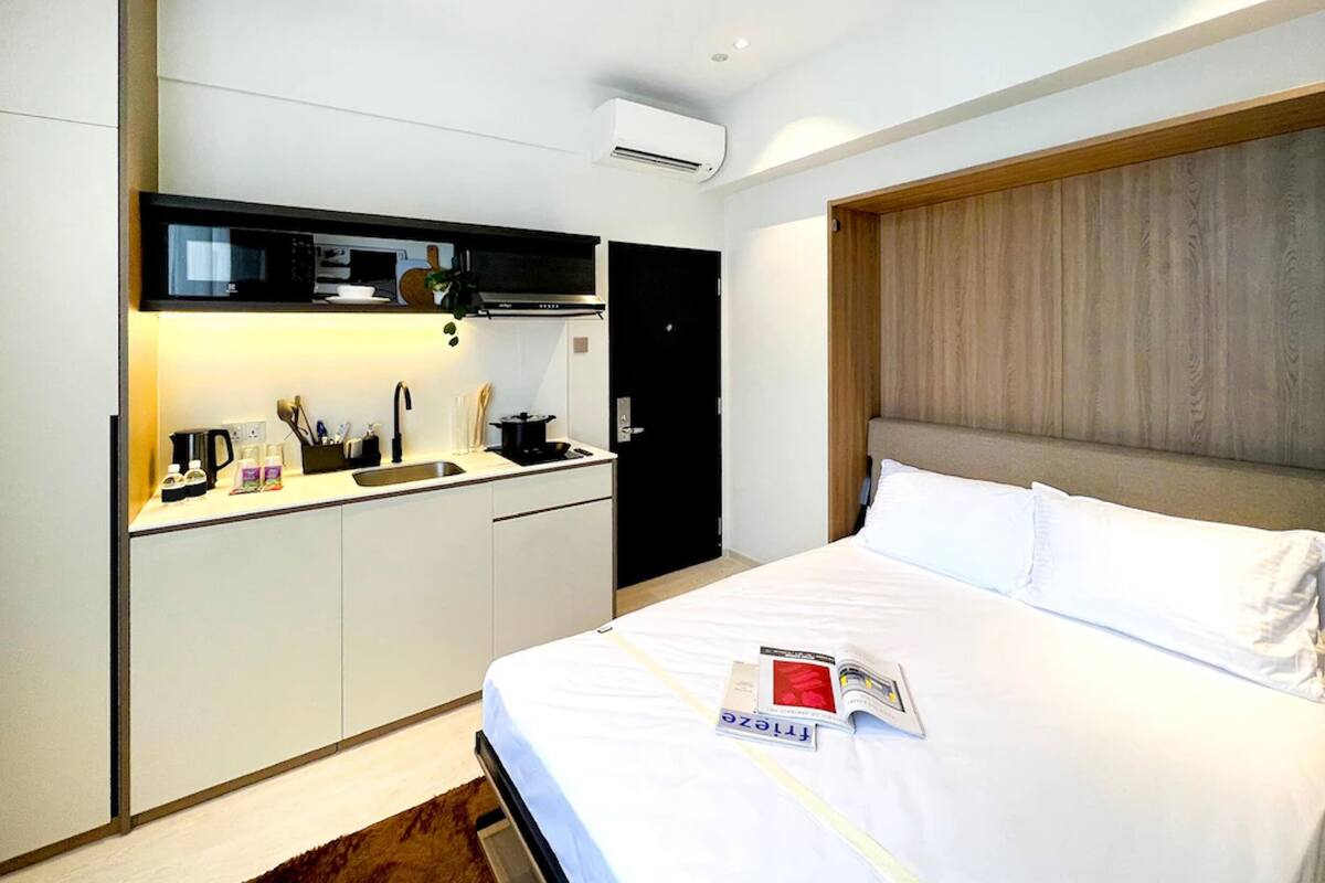 Una camera d'albergo con un letto, una piccola cucina e una testiera in legno.