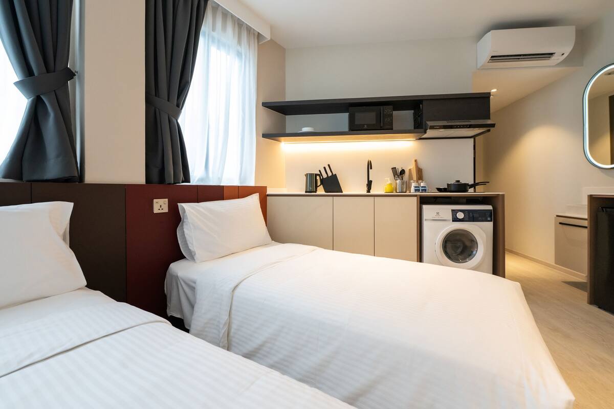 Camera d'albergo con due letti, una lavatrice, un forno a microonde e un angolo cottura.