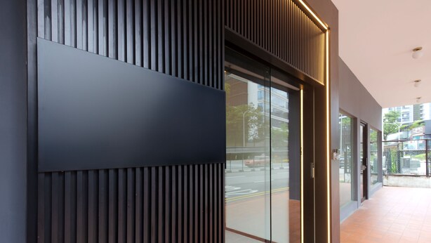 Fachada moderna de un edificio con un gran ventanal y un diseño de paneles verticales de madera.