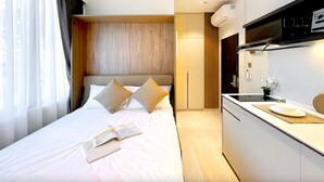 Habitación de hotel moderna con una cama grande, una kitchenette pequeña y vistas a la ciudad.