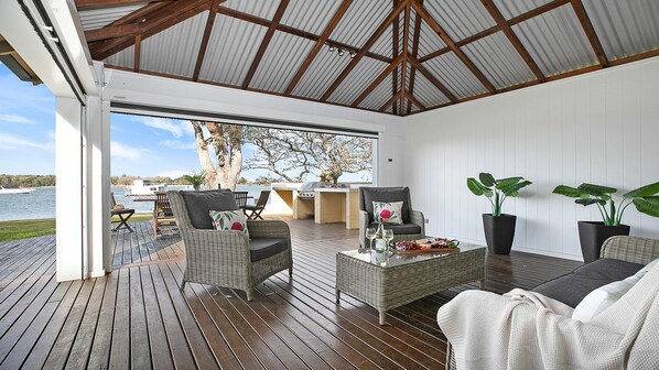 Une terrasse extérieure aménagée avec des meubles en osier, un barbecue et des plantes en pot.