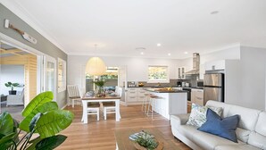 Een moderne keuken met witte kasten, een roestvrijstalen koelkast en een eethoek met een witte tafel en stoelen.