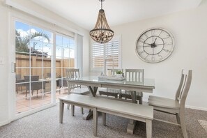 A dining area with a glass table, benches, and a chandelier. - The Salty Escape at Dunes w/ firepit & beach toys (Oceano)