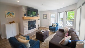 A modern living room with a fireplace, sofas, a coffee table, and a television. - Modern and bright Snowberry condo on Blackcomb Mountain (Whistler)
