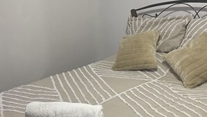 Ein Bett mit einer gestreiften Bettdecke, zwei Kissen und zwei aufgerollten Handtüchern.