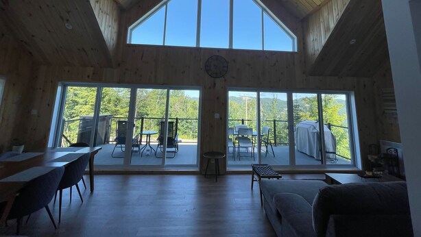 A spacious room with a high ceiling and large windows offering a view of the outdoors.