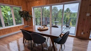 A spacious room with a wooden interior, large windows, and a dining area with a table and chairs.