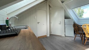 A kitchen with a sink, a wooden dining table, and chairs, a white door, and a skylight. - Stunning Hilltop Nest Unparalleled Views at BnB Ap 17 (Stavanger)