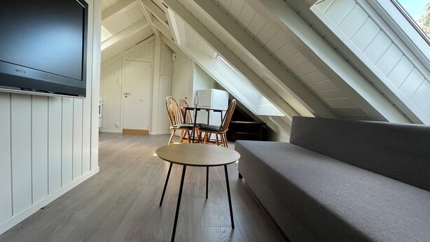 An attic room with a sofa, a table, and chairs. - Stunning Hilltop Nest Unparalleled Views at BnB Ap 17 (Stavanger)