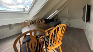 A dining area with a table and chairs, a television mounted on the wall, and a skylight. - Stunning Hilltop Nest Unparalleled Views at BnB Ap 17 (Stavanger)