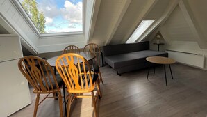 A room with a dining table, chairs, a sofa, a small round table, and a radiator. - Stunning Hilltop Nest Unparalleled Views at BnB Ap 17 (Stavanger)