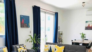 Una sala moderna con un sofá gris, dos sillones, una mesa de centro y un comedor con una mesa y sillas.