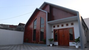 A modern two-story house with a sloped roof, a brick facade, and large windows. - The Maguwo Premiere Kost Ekslusif (Depok)