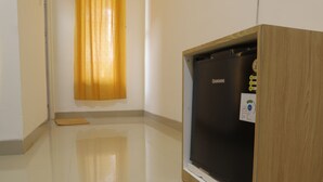 A room with a wooden cabinet, a blackboard, and a yellow curtain. - The Maguwo Premiere Kost Ekslusif (Depok)