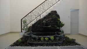 A staircase with a metal railing, a rock garden with various plants, and a door in the background. - The Maguwo Premiere Kost Ekslusif (Depok)