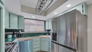 A kitchen with light green cabinets, a stainless steel refrigerator, a dishwasher, and a stove. - A gem Right on Historic RTE 66 with outdoor space.  Walk to the action! (Williams)