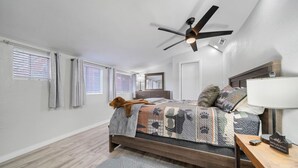 A bedroom with a wooden bed, a ceiling fan, a nightstand, and a window with blinds. - A gem Right on Historic RTE 66 with outdoor space.  Walk to the action! (Williams)