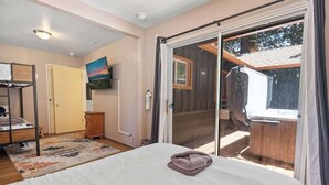 Een slaapkamer met een bed, een raam, een schuifpui, een schilderij en een houten kast.