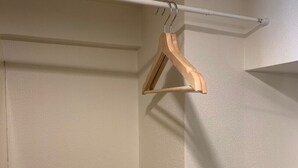 A room with a white textured wall, a white ceiling, and a wooden hanger on a white rod.