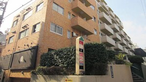 A multi-story residential building with balconies, a gated entrance, and a signboard.