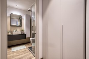 A modern bathroom with a glass shower enclosure, a large mirror, and a dark vanity. - Sardinia Re - Indigo Suites (Alghero)