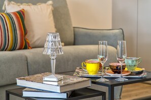 A cozy living room with a sofa, a coffee table, and a lamp. - Sardinia Re - Indigo Suites (Alghero)